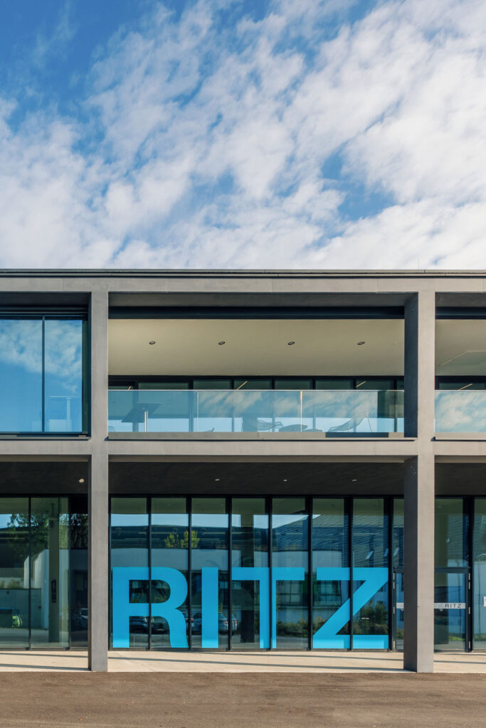 Frontalansicht der Glasfassade des RITZ Innovationszentrums mit großem blauen RITZ-Schriftzug