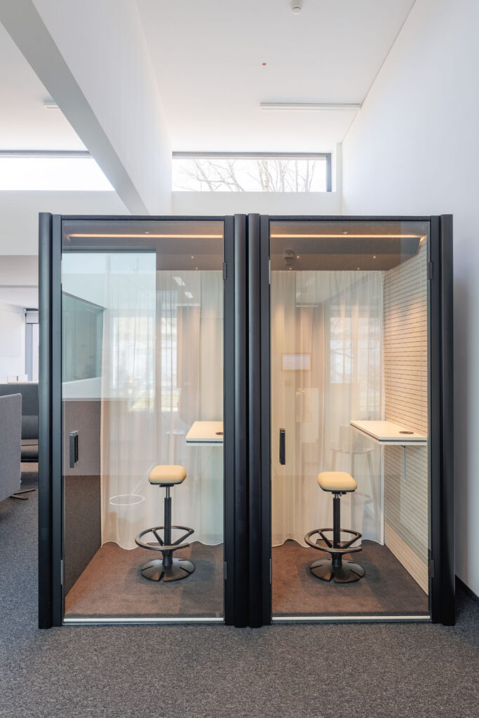 Zwei moderne, schallgedämmte Telefonboxen mit Hocker und Tisch im Innenbereich des RITZ Innovationszentrums.