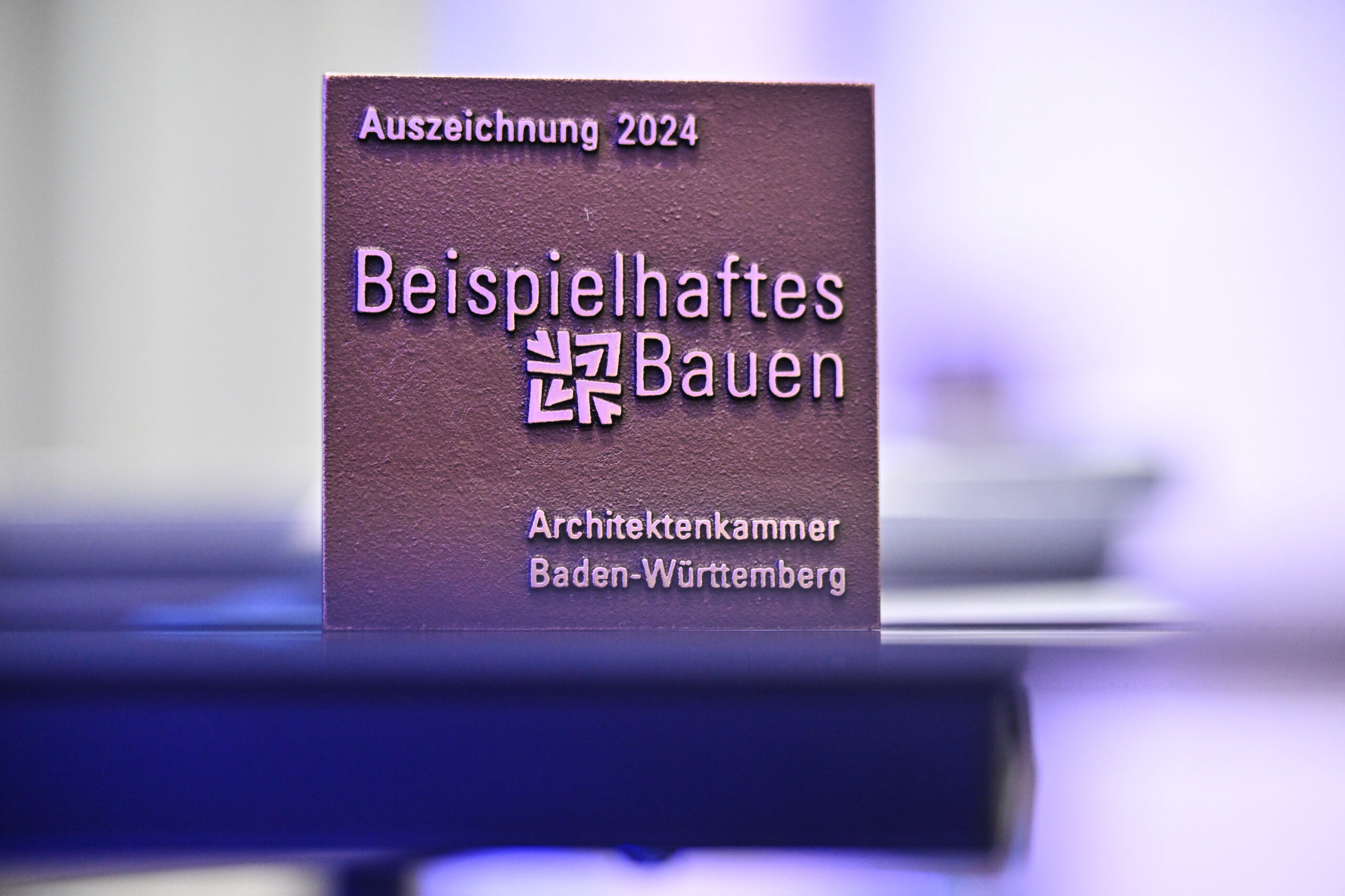 Plakette der Architektenkammer Baden-Württemberg mit der Aufschrift „Auszeichnung 2024 – Beispielhaftes Bauen“
