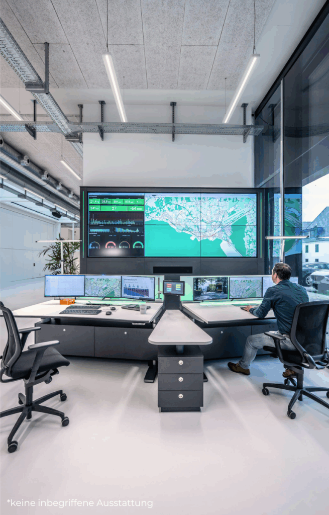 Moderne Smart-City-Leitstelle mit großer Bildschirmwand, mehreren Monitoren und einem Mann an einem Arbeitsplatz mit Karten- und Datenanzeige.