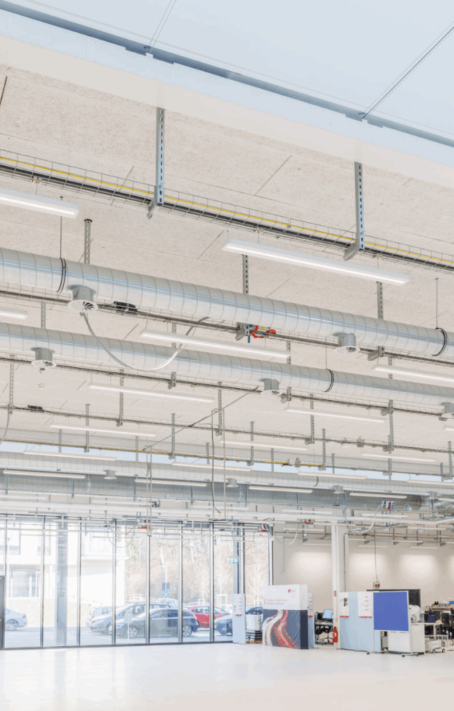 Große Produktionshalle mit Tageslichteinfall, modularen Stellwänden und technischer Infrastruktur.