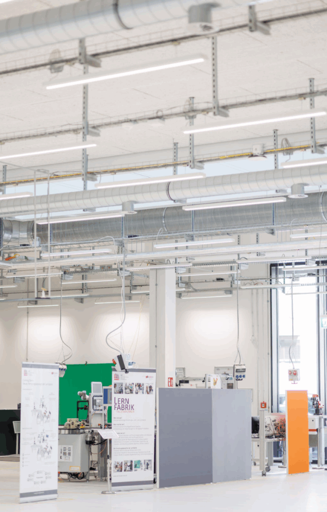 Übersicht über den Factory Space mit verschiedenen Arbeitsstationen, Rollups und technischer Ausstattung der Lernfabrik Fallenbrunnen.