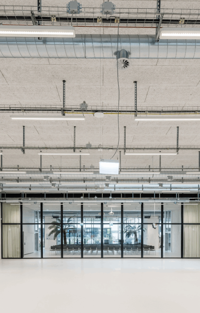 Blick vom Factory Space auf den angrenzenden Veranstaltungsbereich mit bodentiefen Fenstern und Bestuhlung.