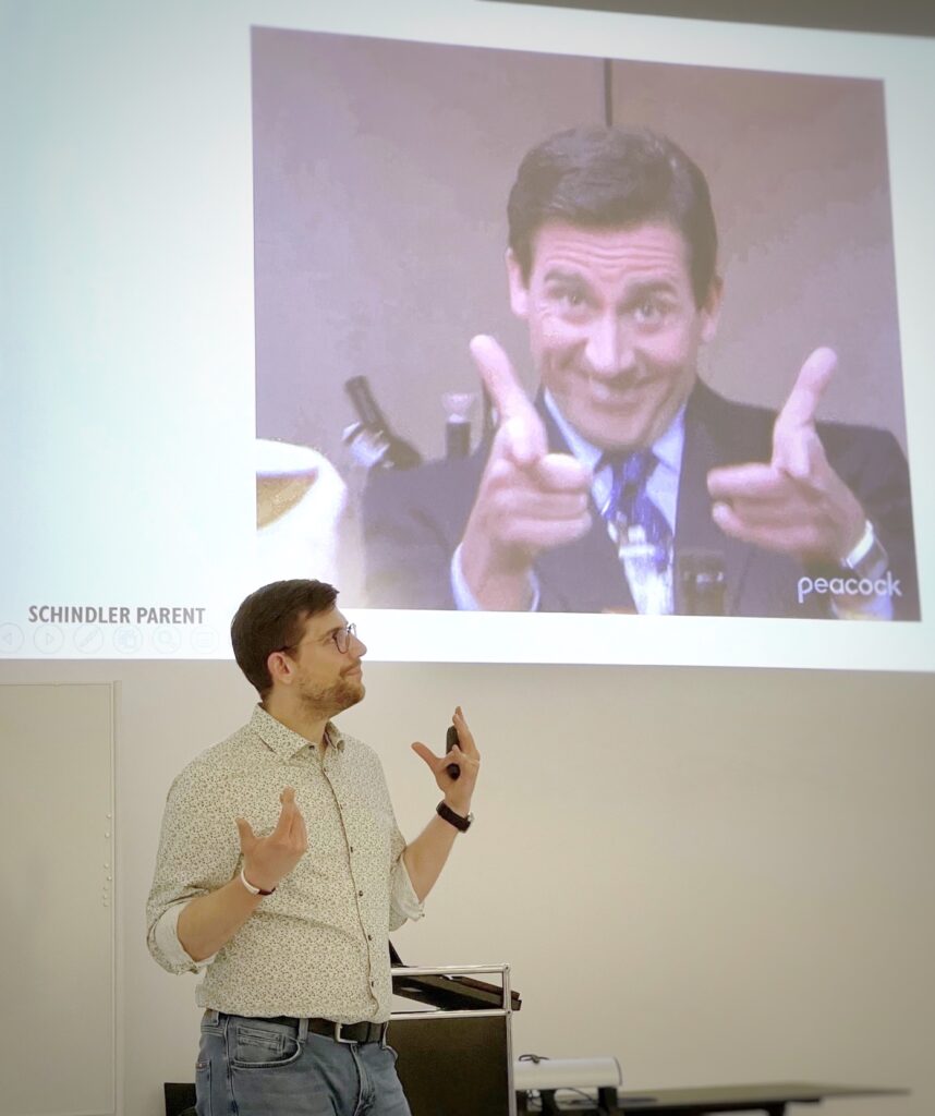 Sascha Schmidt beim Vortrag im Rahmen von „Breakfast & Brainfood“, im Hintergrund ein GIF von Steve Carell als Michael Scott aus „The Office“.
