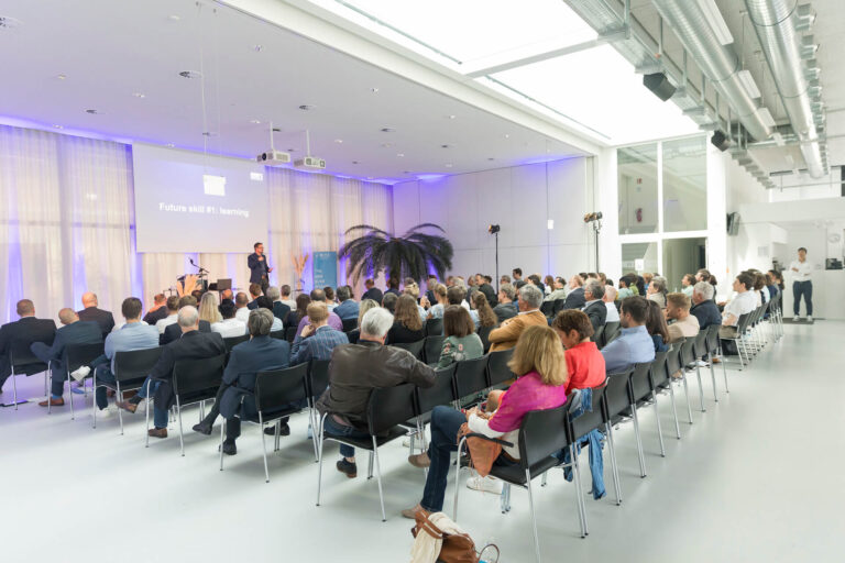 Dr. Boris Nikolai Konrad steht auf der Bühne im RITZ Innovationszentrum und spricht vor einem voll besetzten Saal. Auf der Leinwand hinter ihm ist der Titel seiner Keynote zu sehen: „Future Skill #1: Learning“. Das Publikum sitzt in Reihen, aufmerksam zugewandt, die Atmosphäre ist konzentriert.