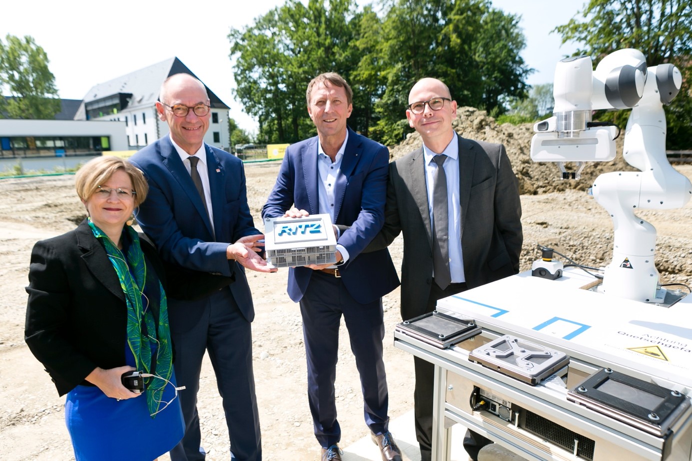 RITZ-Geschäftsführerin Manuela Meske-Schubert, Landrat Lothar Wölfle, Erster Bürgermeister Dr. Stefan Köhler und Dr. Arndt Oschmann (Ministerium für Wirtschaft BW) bei der Grundsteinlegung; gemeinsam halten sie symbolisch ein RITZ-Modell, rechts im Bild ein Roboterarm.