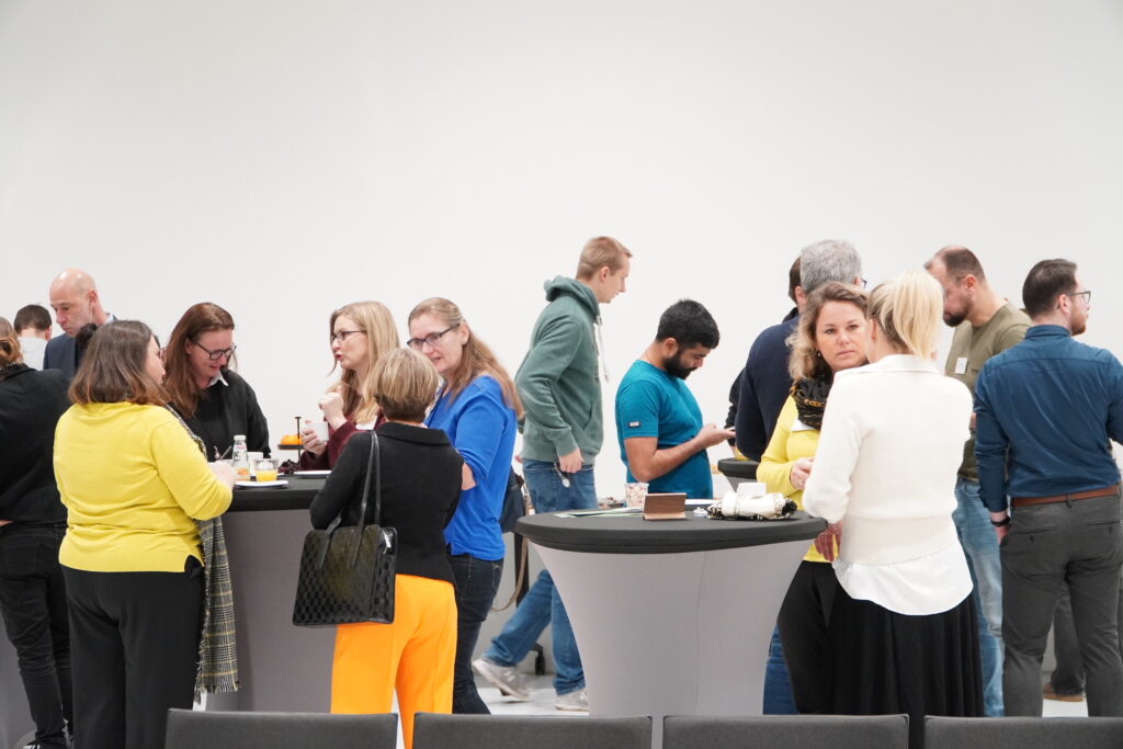 Teilnehmende des Breakfast & Brainfood-Formats im RITZ Friedrichshafen stehen in kleinen Gruppen an Stehtischen, essen, trinken und tauschen sich aus.