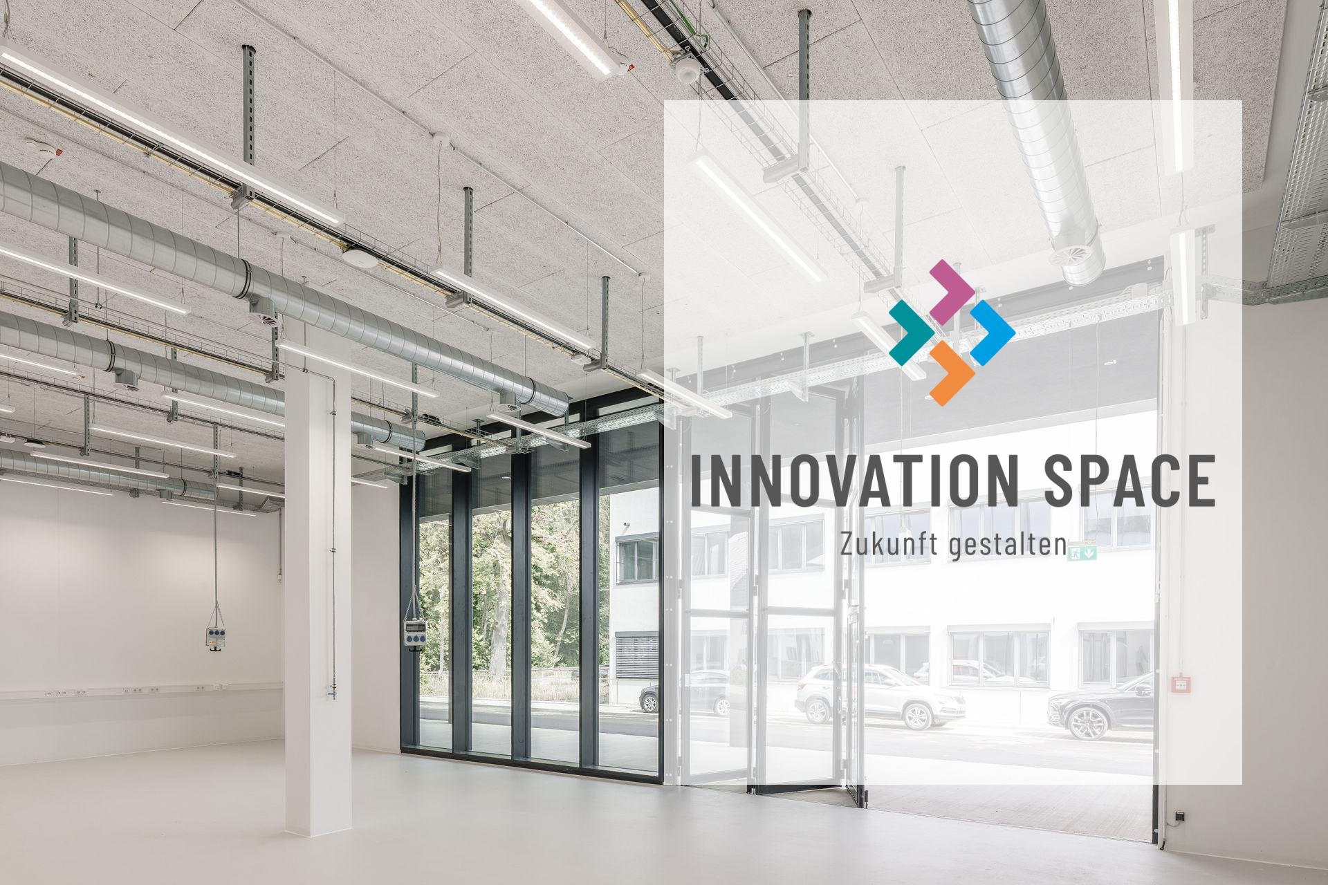 Moderner, heller Raum mit großen Fensterfronten im RITZ Innovationszentrum. Sichtbare Deckeninstallationen und technische Anschlüsse deuten auf flexible Nutzungsmöglichkeiten hin. Im Vordergrund steht transparent eingeblendet das Logo des Innovation Space mit dem Slogan ‚Zukunft gestalten‘.