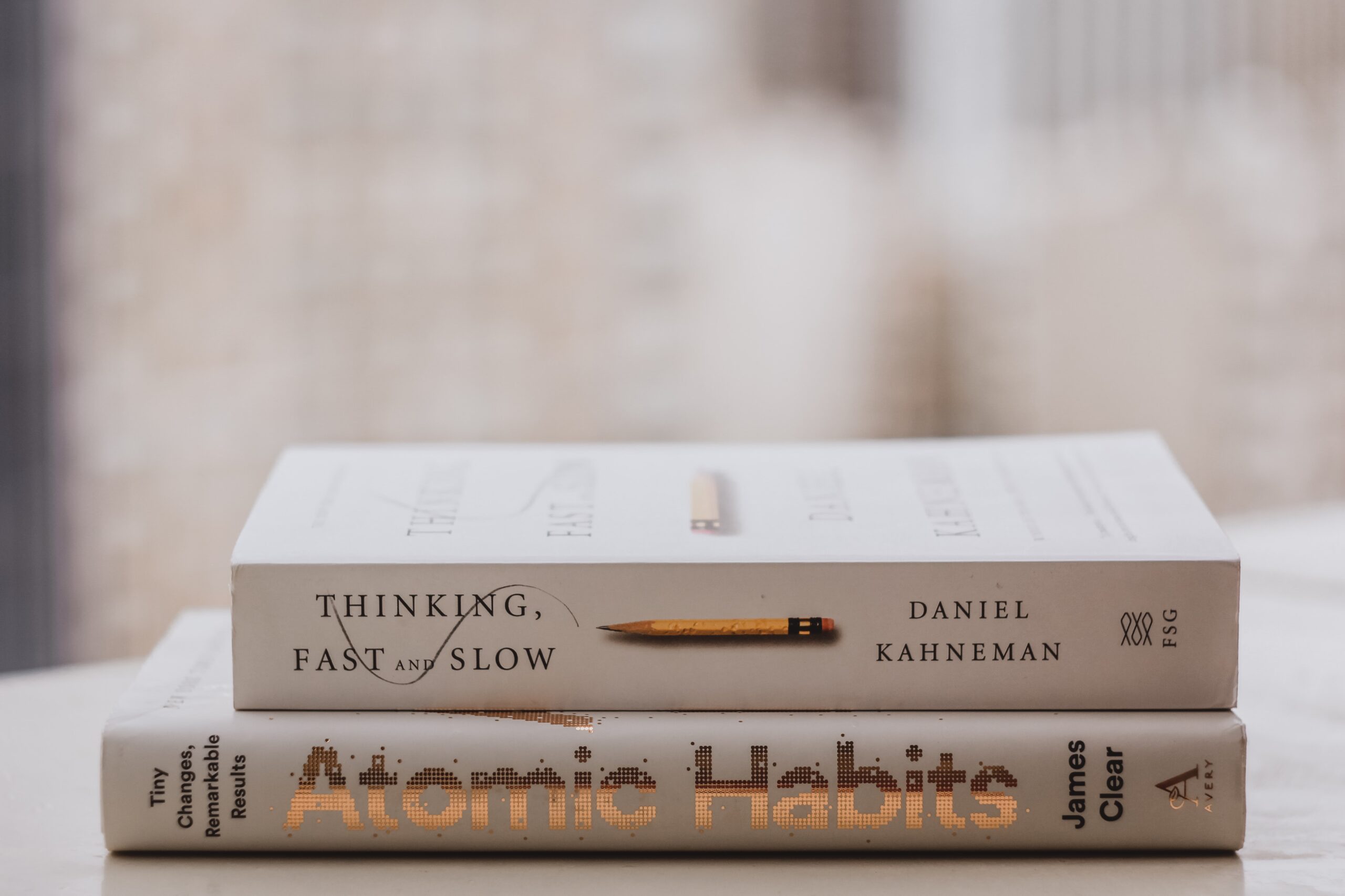 Zwei Bücher aufeinander, "Atomic Habits" und "Thinking, Fast and Slow"