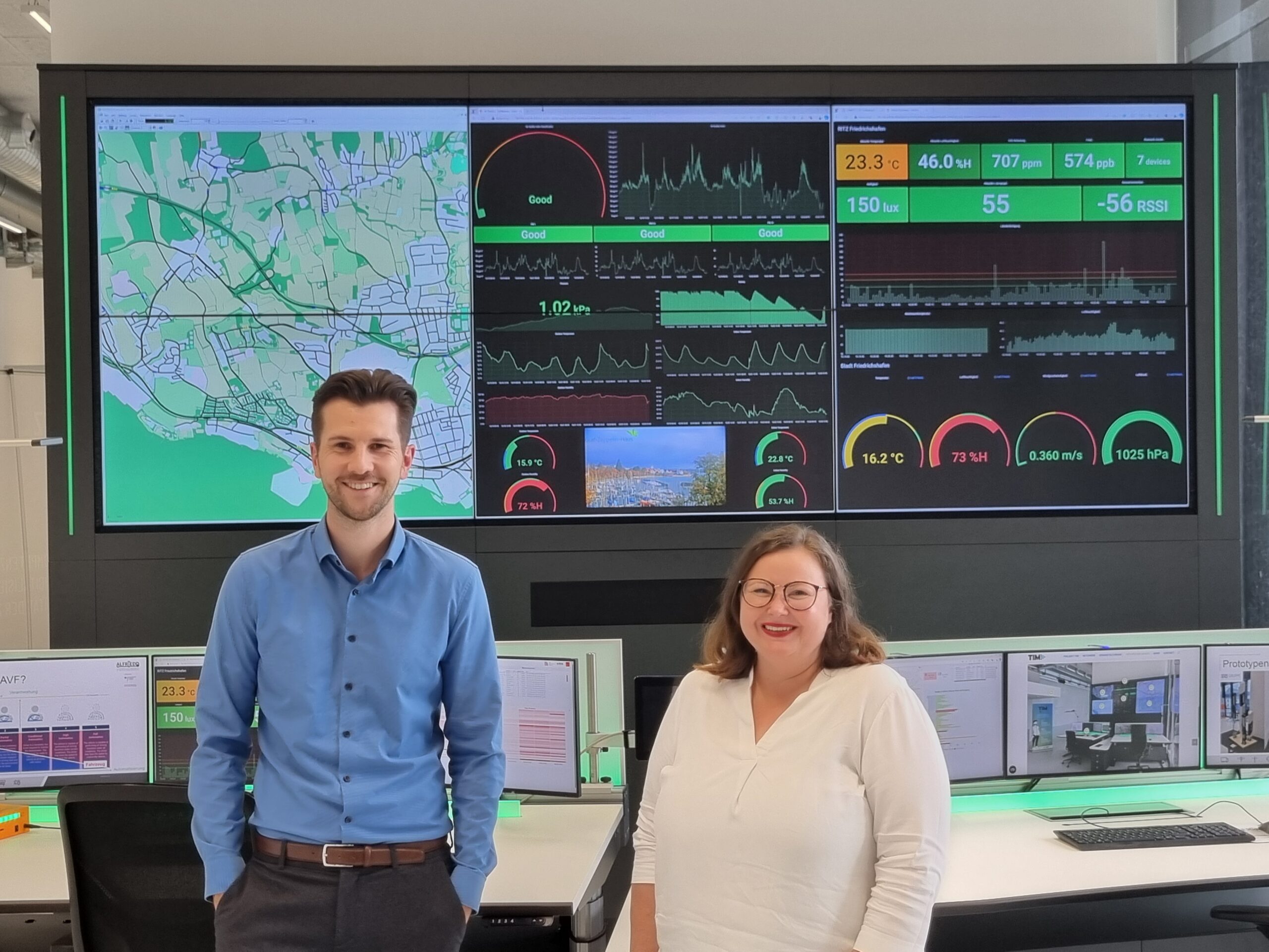 Links Philipp Röper, Geschäftsführer von Tri.Merge, rechts Celina Herbers, Teamleiterin am IWT, im Hintergrund die Smart-City-Leitstelle mit einem großen Monitor und Steuerelementen