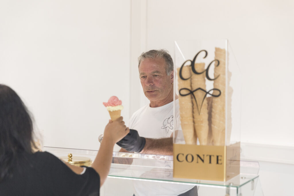 Eisausgabe beim Jubiläum „1,5 Jahre RITZ“: Ein Mitarbeiter reicht einer Besucherin ein Eis an einem Cateringstand.