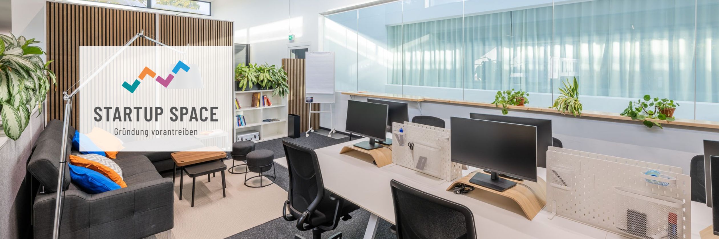 Coworking-Büro Startup Space im RITZ mit Arbeitsplätzen, Monitoren, Sitzecke und Pflanzen, Logo „Gründung vorantreiben“