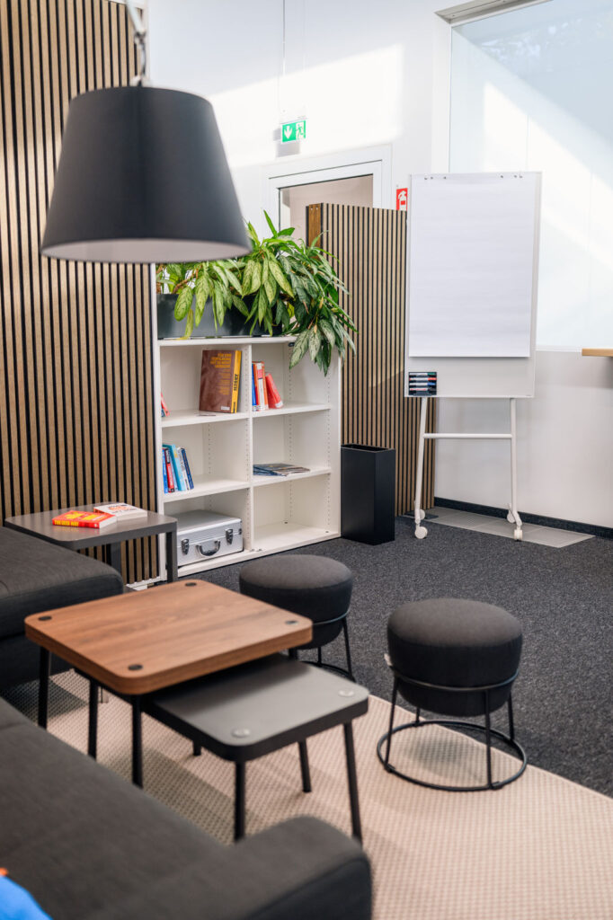 Lounge-Bereich im Startup Space mit Sofa, Bücherregal, Pflanzen und Flipchart